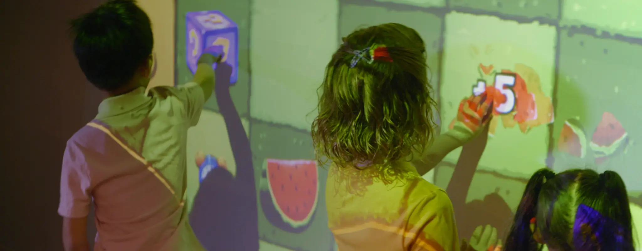 Children playing on an interactive wall projection in a dimmed sensory-friendly space